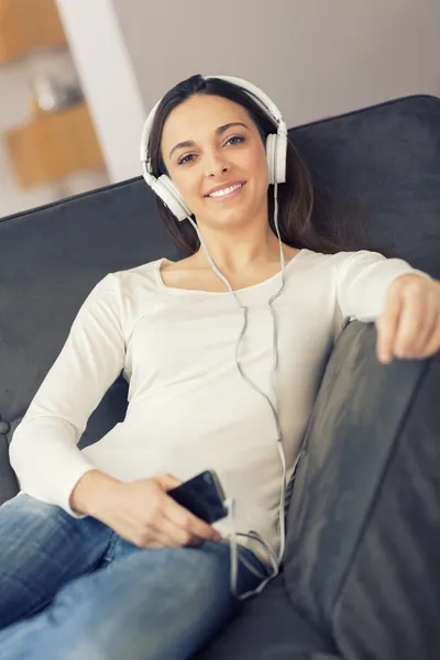 Entspannte Frau hört Musik zu Hause auf dem Sofa — Stockfoto