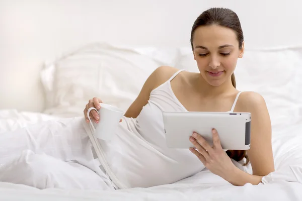 Junges Mädchen mit Tablette im Bett — Stockfoto