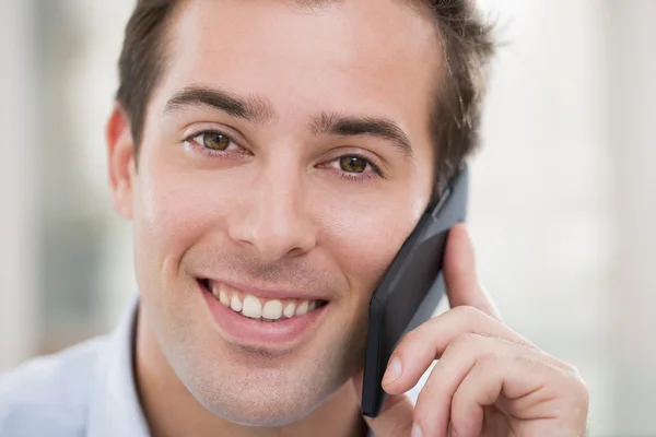 Lachende jonge man op de mobiele telefoon — Stockfoto