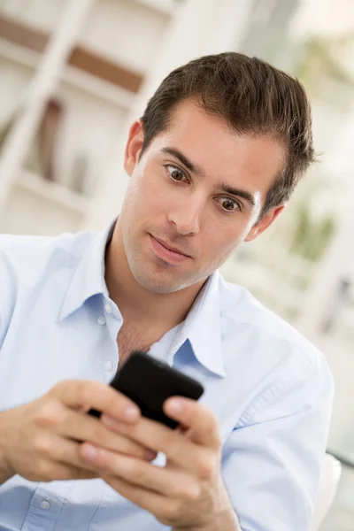 Junger schöner Mann schreibt SMS aufs Handy. — Stockfoto