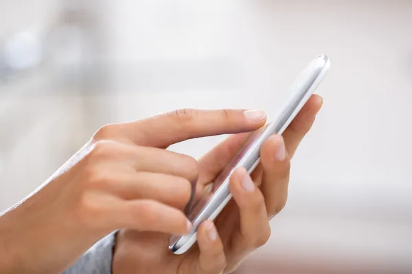 Primer plano de las manos de la mujer usando el teléfono celular . — Foto de Stock