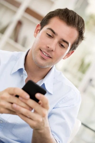 Young handsome man writting SMS on mobile phone. Royalty Free Stock Images