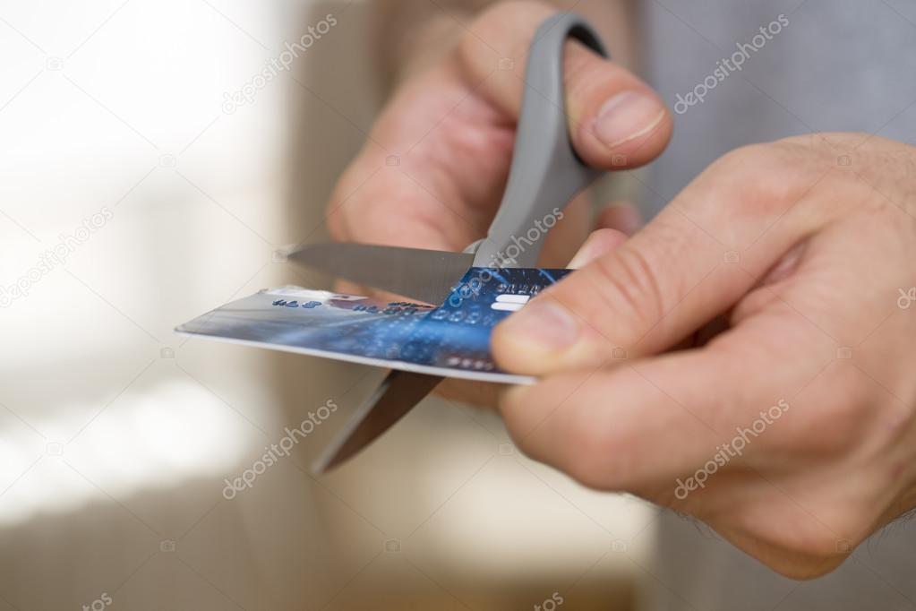 Man Cutting Credit Card with scissors over a background