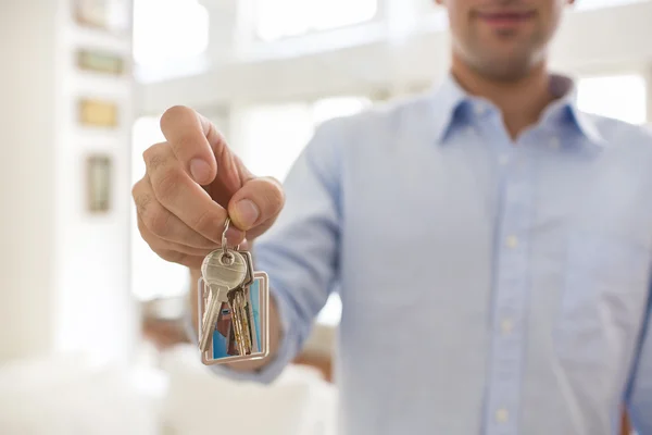 En man håller i sin hand nycklarna till sitt hus, inomhus. — Stockfoto