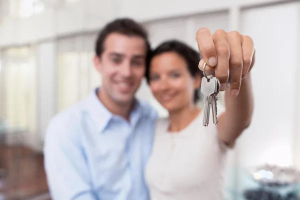 Feliz joven pareja sonriente mostrando las llaves de su nueva casa — Foto de Stock