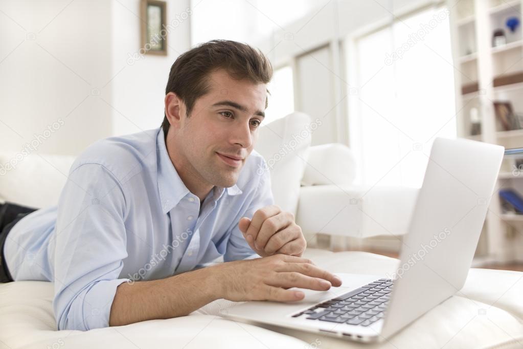 Man on couch using laptop at home