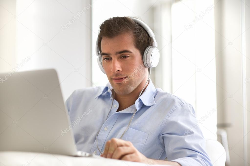 Portrait of young handsome guy with laptop using headset