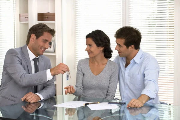 Real-estate agent giving keys to new property owners — Stock Photo, Image