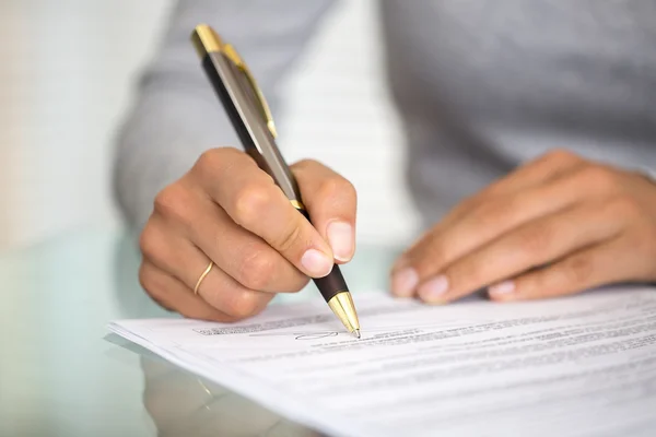 Mujer en el escritorio de la oficina firmando un contrato con enfoque superficial en si —  Fotos de Stock