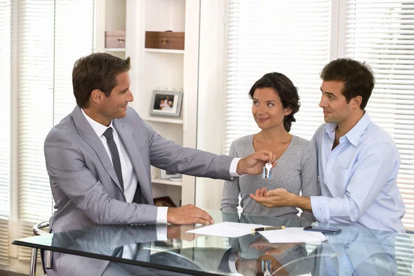 Real-estate agent giving keys to new property owners — Stock Photo, Image