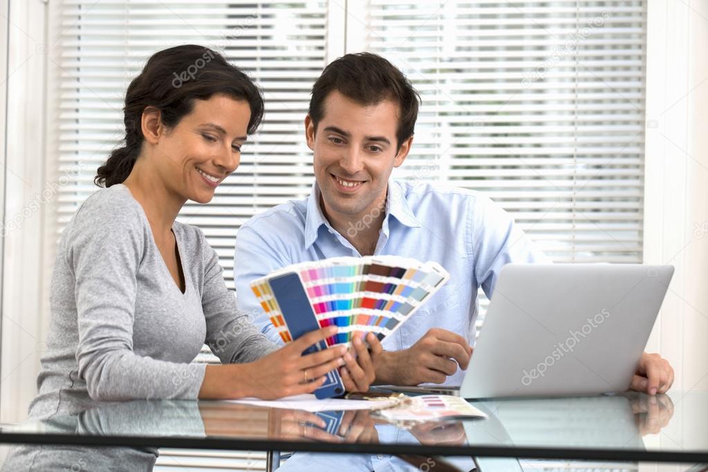 Happy couple choosing colours to paint new house