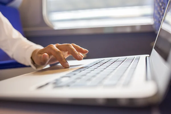 Primeros planos de las manos de la mujer escribiendo en un teclado portátil en el tren — Foto de Stock