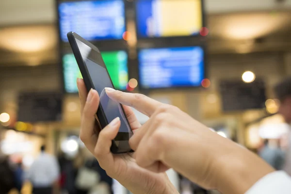 Cierre de manos mujer usando su teléfono celular en la estación, backgro —  Fotos de Stock