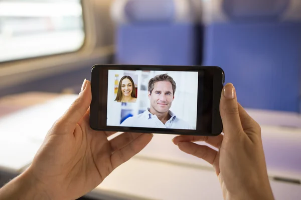 Primer plano de una mano femenina sosteniendo un teléfono celular durante un skype vid — Foto de Stock