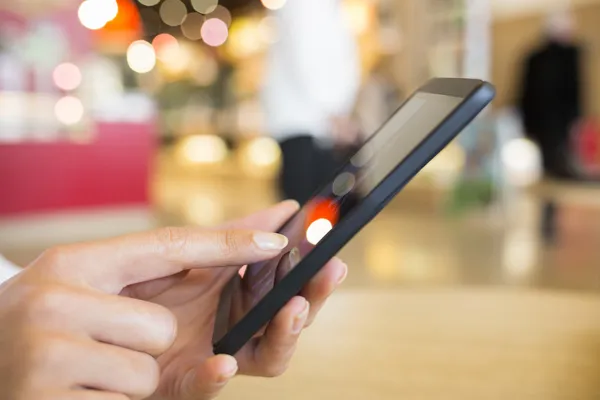 Närbild på händer kvinnan använder sin mobiltelefon på en station — Stockfoto