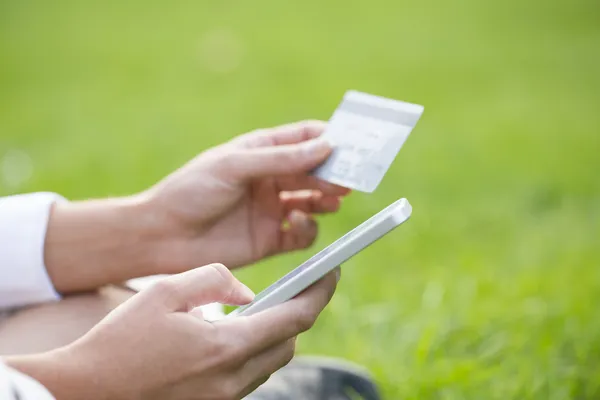 Närbild kvinnas händer håller ett kreditkort och använder cell phon — Stockfoto