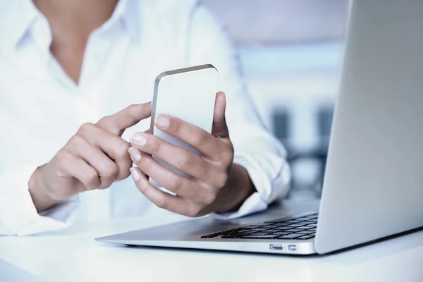 Mãos de mulher com telefone inteligente e teclado de computador — Fotografia de Stock