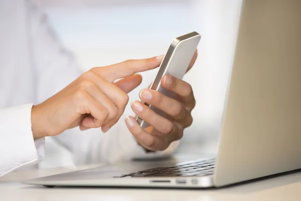 Woman hands with smart phone and computer keyboard — Stock Photo, Image