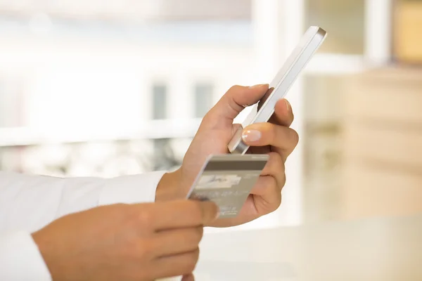 Närbild kvinnas händer håller ett kreditkort och använder cell phon — Stockfoto