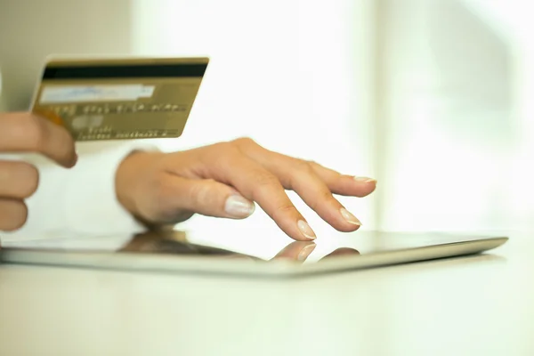 Close-up woman's hands holding a credit card and using tablet pc Royalty Free Stock Images