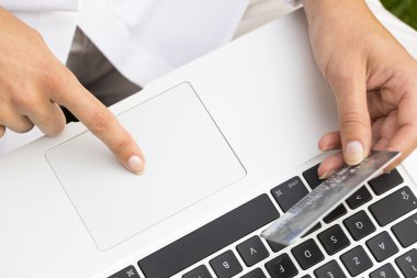 kredi kartı tutan ve bilgisayar kullanarak yakın çekim kadının eller