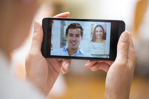 Gros plan d'une main féminine tenant un smartphone pendant un skype vid — Photo