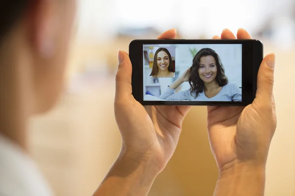 Gros plan d'une main féminine tenant un smartphone pendant un skype vid — Photo