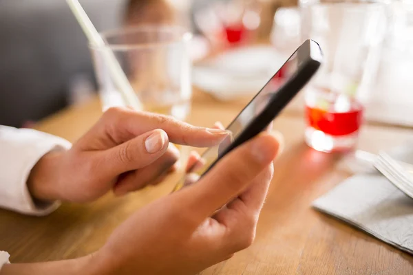 Close up van handen vrouw met behulp van haar mobiele telefoon in restaurant — Stockfoto