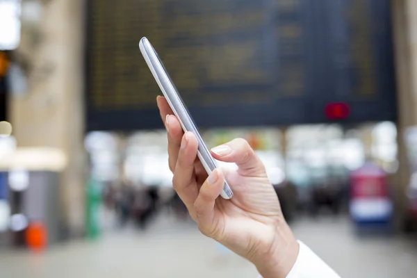 Close-up van handen vrouw met behulp van haar mobiele telefoon in de treinstation, b — Stockfoto