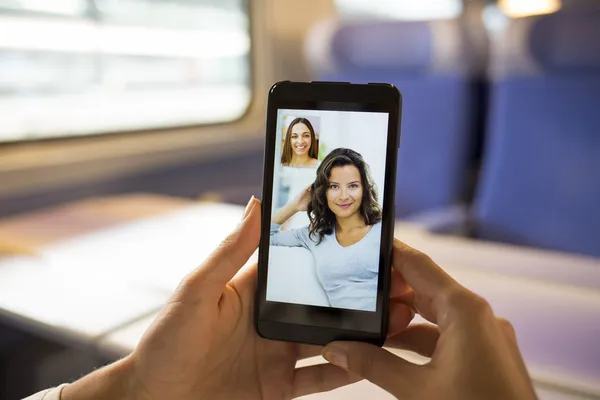 Close-up de uma mão feminina segurando um telefone celular durante um vídeo skype — Fotografia de Stock