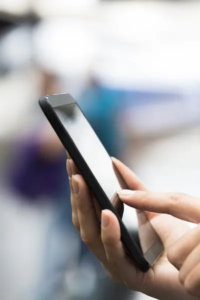 Close up van handen vrouw met behulp van haar mobiele telefoon op een treinstation — Stockfoto