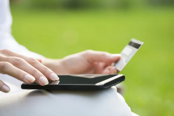 Primeros planos de las manos de una mujer sosteniendo una tarjeta de crédito y utilizando el teléfono celular — Foto de Stock