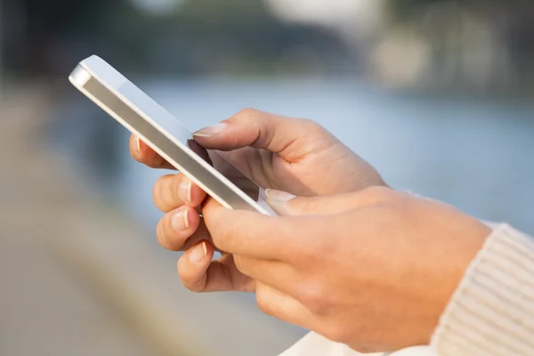 Telefono cellulare in mano a una donna, canale di sfondo — Foto Stock