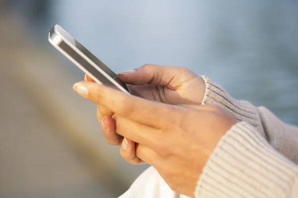Мобильный телефон в руке женщины, фоновая чанна — стоковое фото