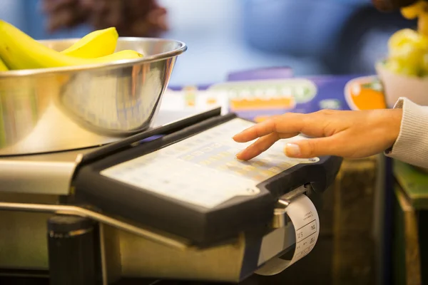 Woman weighing banana in supermarket — Stock Photo, Image