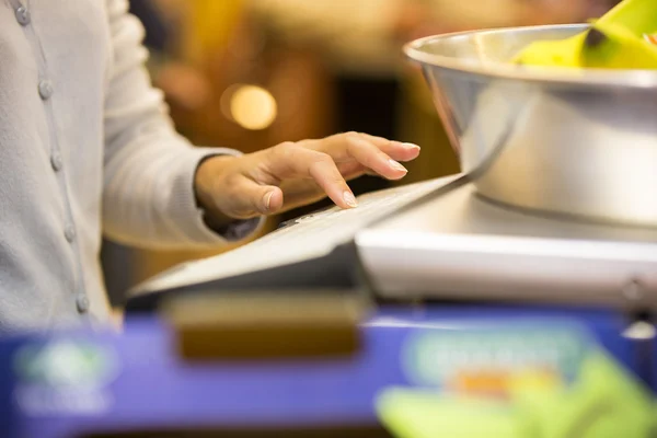 Woman weighing banana in supermarket — Stock Photo, Image