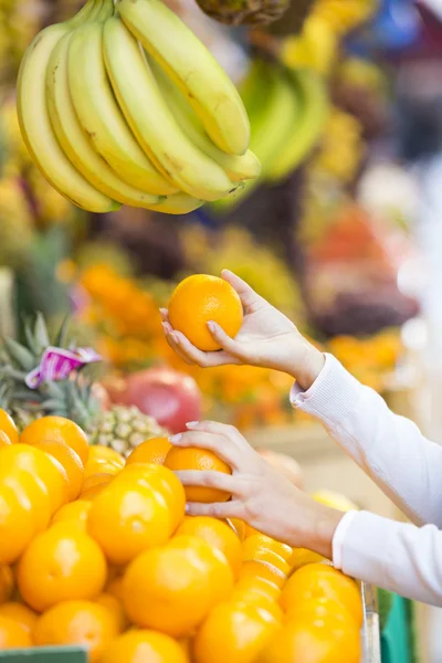 Kadın bir pazarda sebze ve meyve satın alır. — Stok fotoğraf