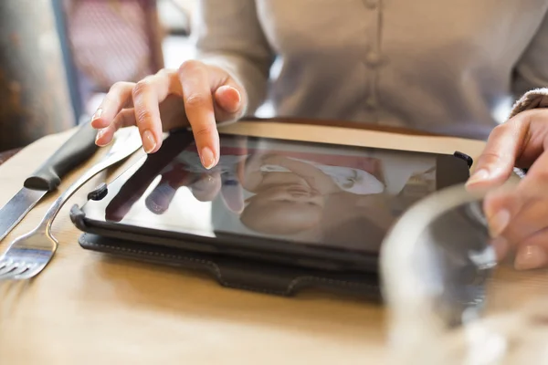 Woman using tablet pc in a cafe, baby picture — Stock Photo, Image