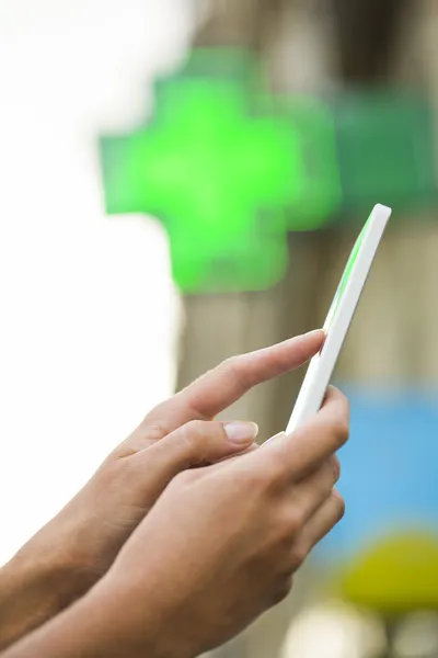 Vrouw met behulp van haar mobiele telefoon in de voorste neon teken farmacie — Stockfoto