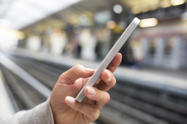 cep telefonu ile metro platformda bekleyen kadın