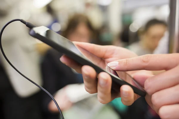 Woman using her cell phone in subway, she listens to music with — Stock Photo, Image