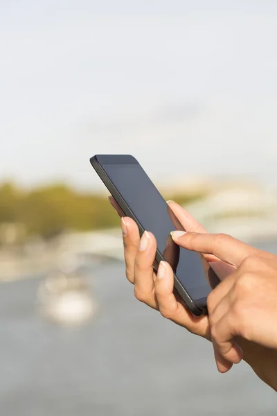 Vrouw met behulp van haar mobiele telefoon, achtergrond Parijs — Stockfoto