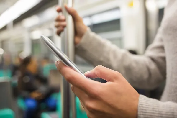 Mulher usando seu telefone celular na plataforma do metrô — Fotografia de Stock