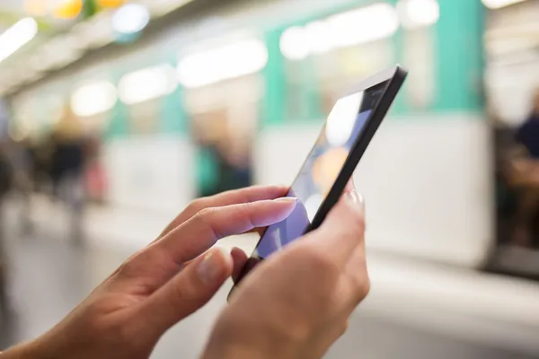 Mulher usando seu telefone celular na plataforma do metrô — Fotografia de Stock