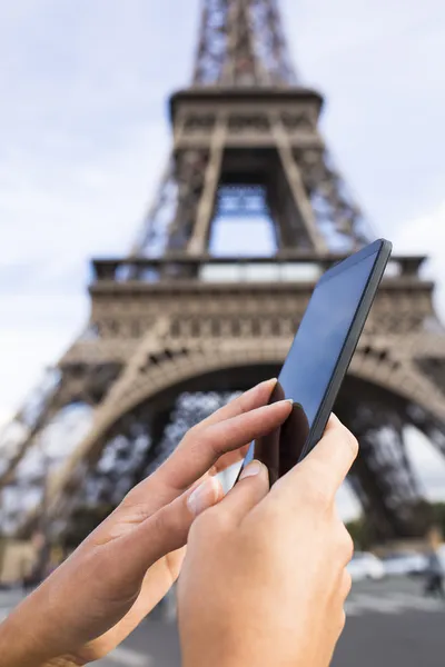 Mulher usando seu telefone inteligente na frente da Torre Eiffel — Fotografia de Stock