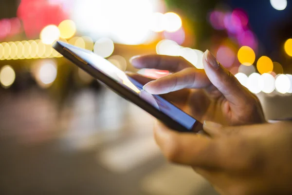 Mujer usando su teléfono móvil en la calle, ambiente de luz nocturna Imágenes de stock libres de derechos