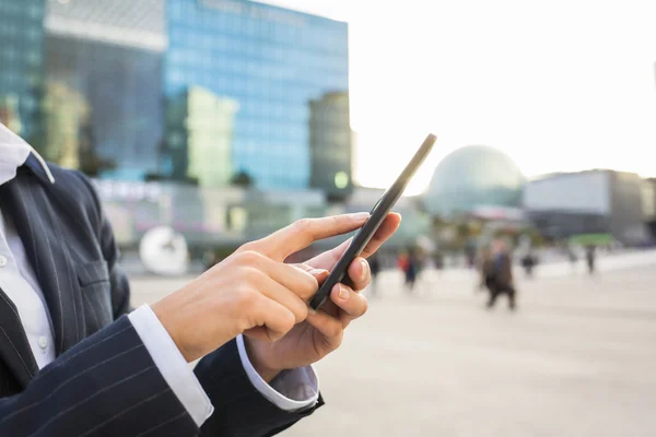 Zakenvrouw met behulp van haar slimme telefoon in werkomgeving — Stockfoto