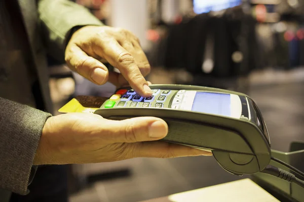 Primer plano de un hombre usando el teléfono móvil en la tienda de ropa — Foto de Stock