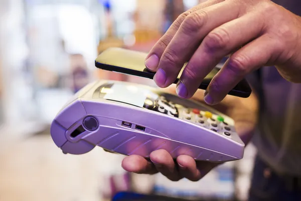 Hombre que paga con tecnología NFC en el teléfono móvil, en la farmacia — Foto de Stock