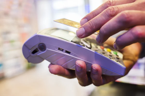 Homem que paga com tecnologia NFC no cartão de crédito, na farmácia — Fotografia de Stock